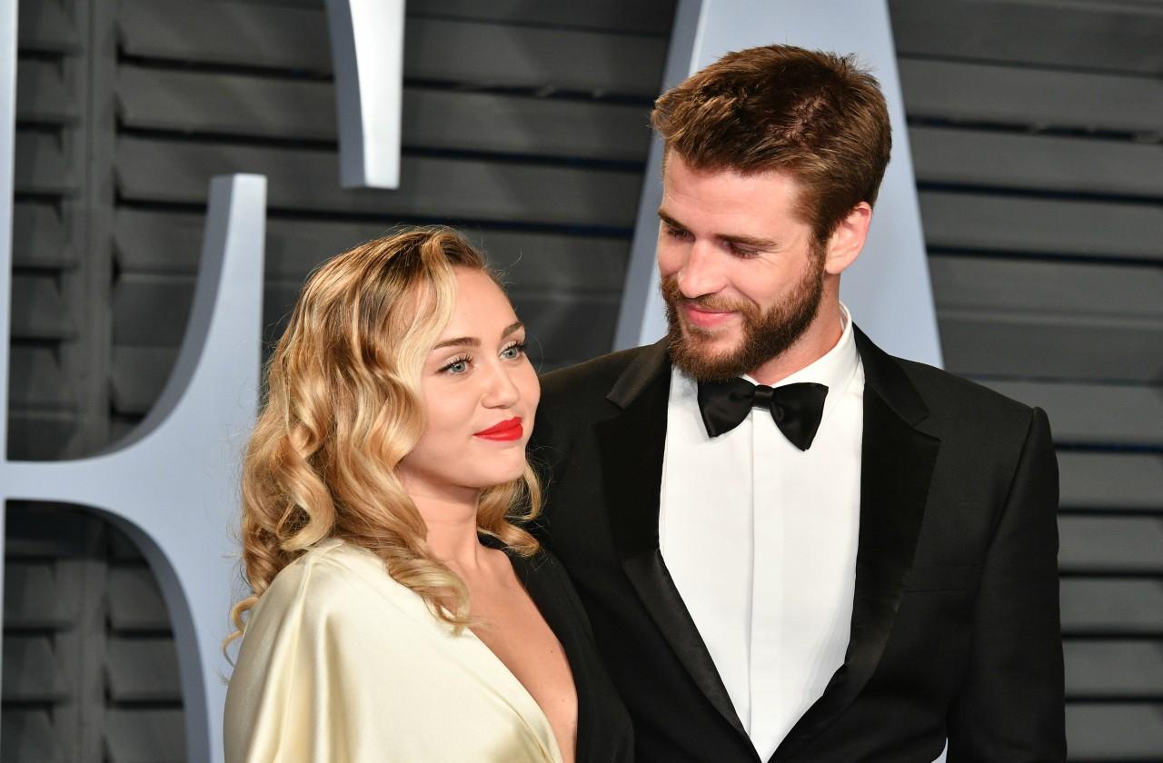 Liam Hemsworth stares adoringly at Miley Cyrus in front of the Vanity Fair sign