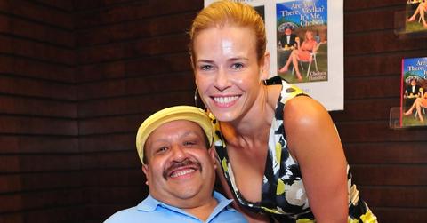 Chuy Bravo wears a blue shirt while standing next to Chelsea Handler who is in a dress with abstract print on it.