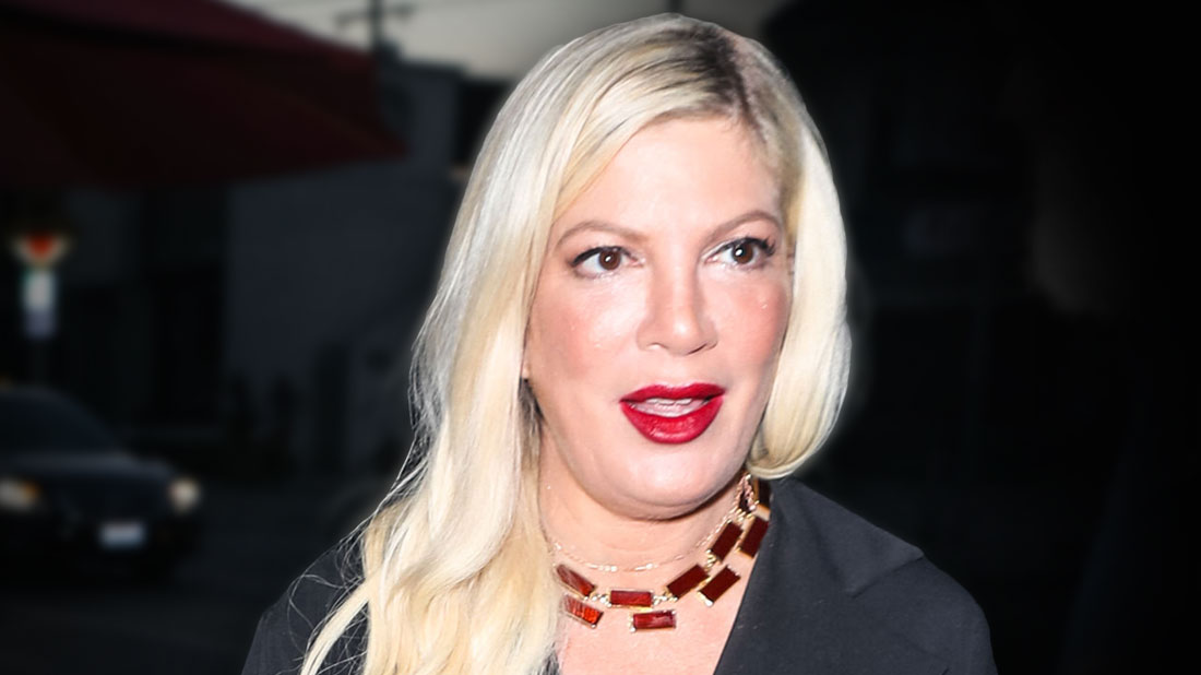 Tori Spelling Wearing Red Lipstick, Black Shirtdress With Brownish Red Necklace