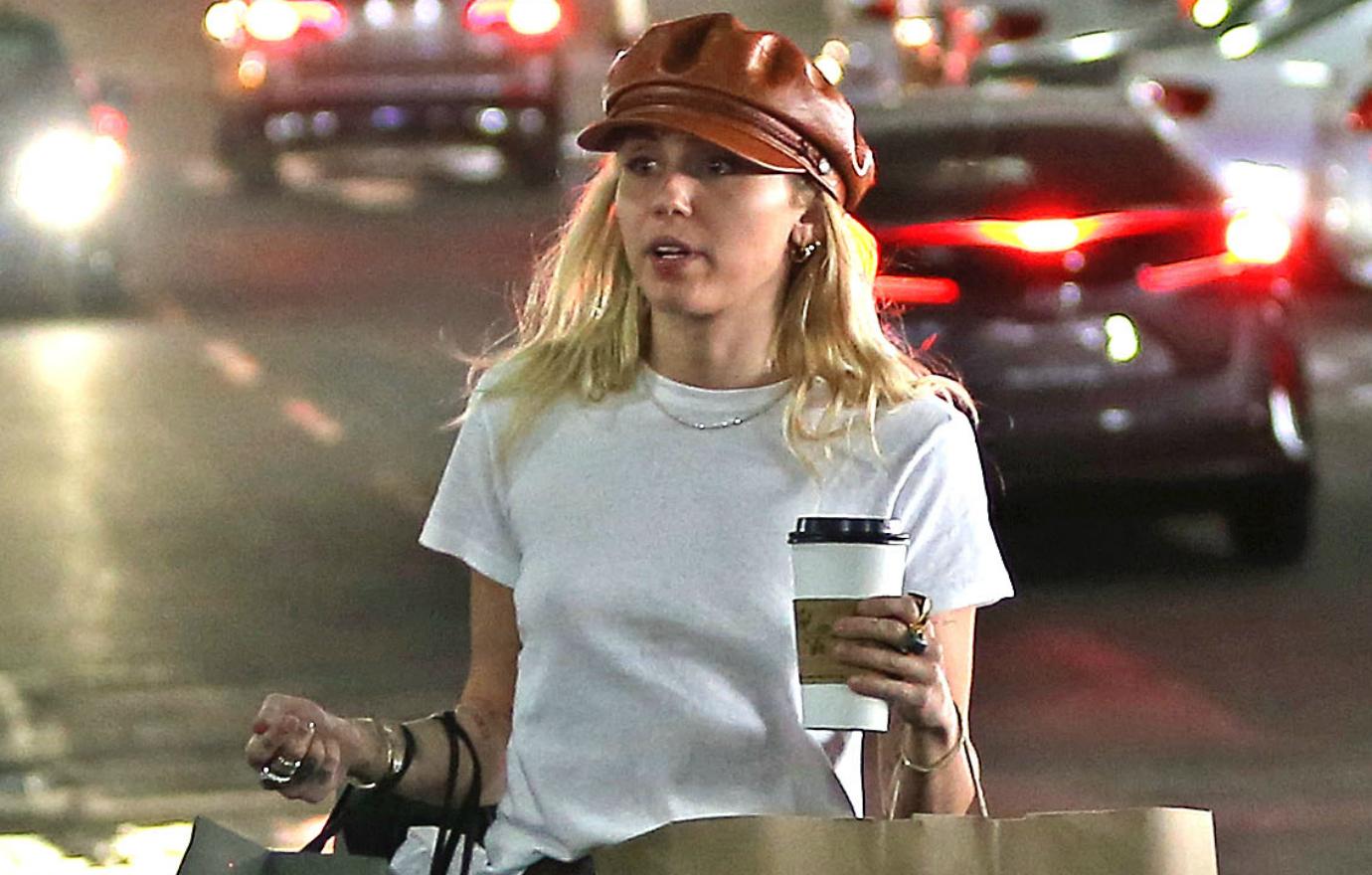 Miley Cyrus went shopping in a white T and a maroon hat.