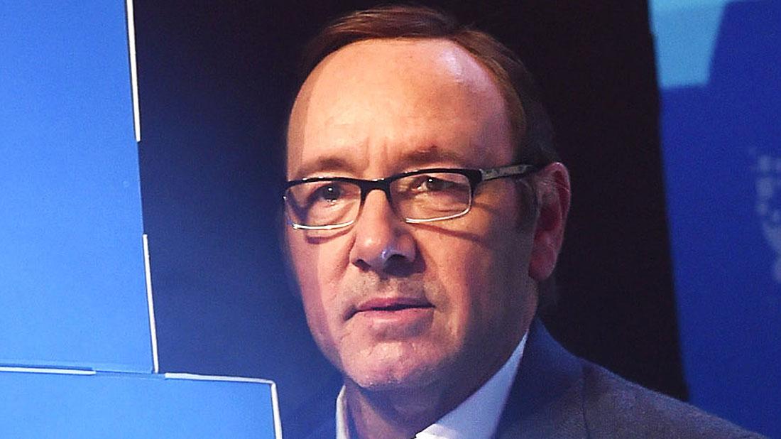 Kevin Spacey With Glasses, White Shirt and Grey Jacket With Blue Background