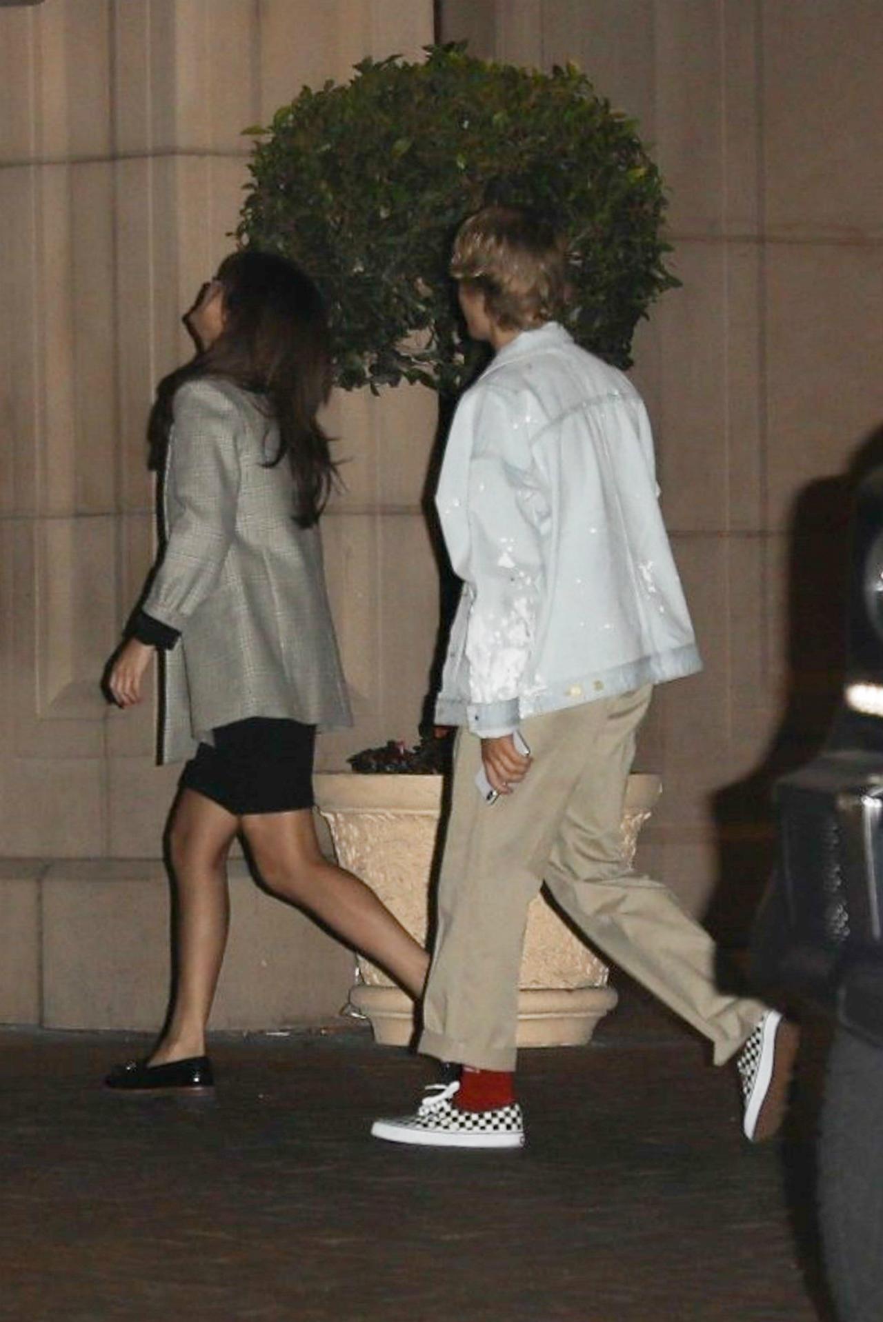 Selena Gomez wears a gray jacket and black skirt on a Valentine's Day date with Justin Bieber, wearing a jacket, khaki pants, red socks, and black and white sneakers.