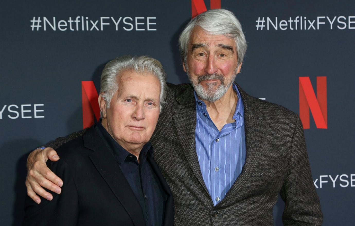 Sam Waterston, in dark suit and blue jacket has his arm around Martin Sheen, who wears a black suit, on the red carpet.