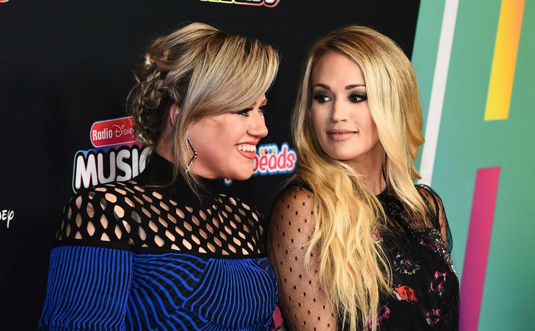 Carrie Underwood and Kelly Clarkson stand next to each other on the red carpet.