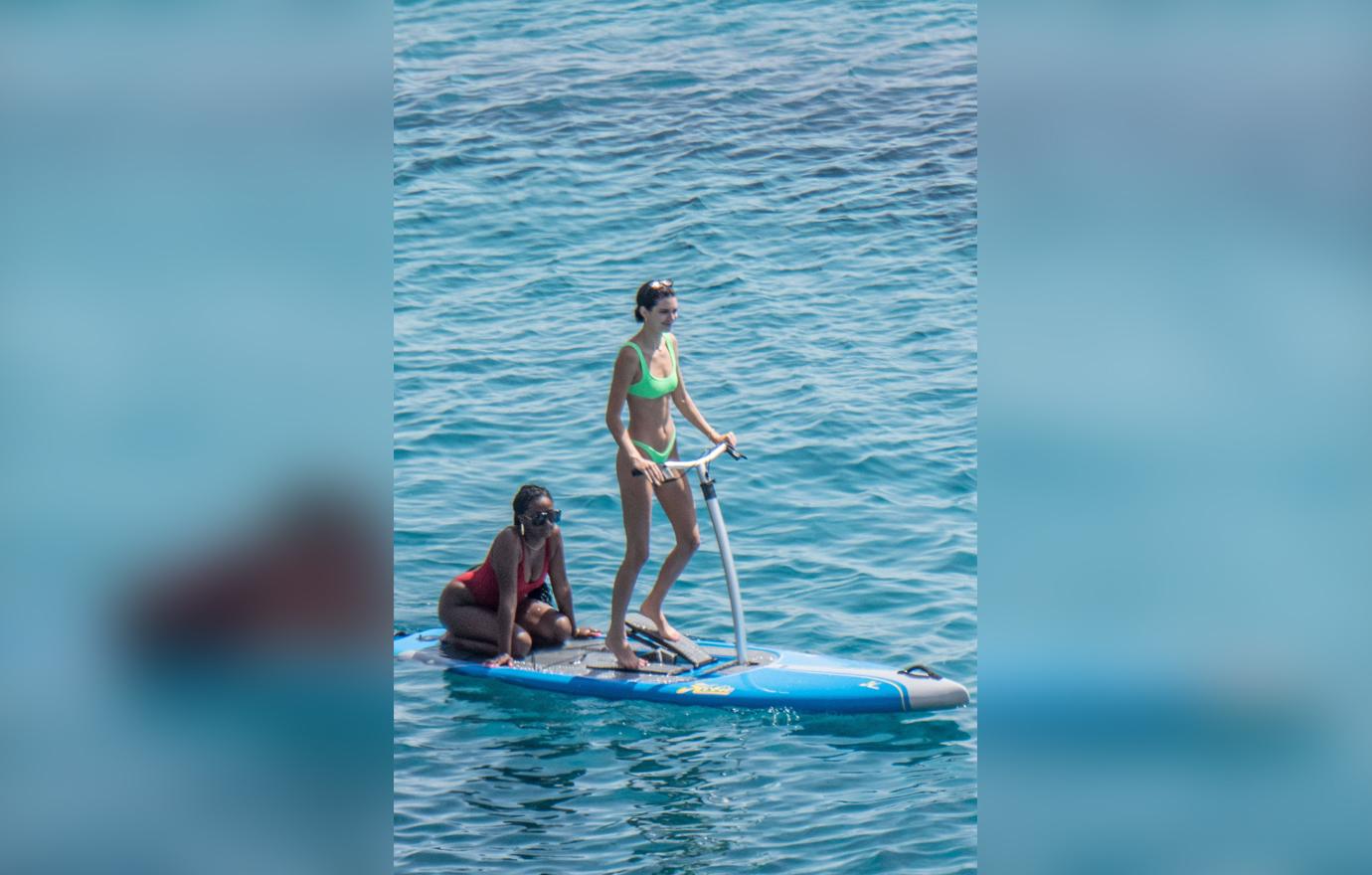 Kendall Jenner wears a neon-green bikini while having fun with friends paddle boarding in Mykonos.